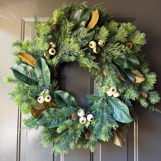 Evergreen wreath with clusters of magnolia leaves and creamy white pods/berries, and mini pinecones.