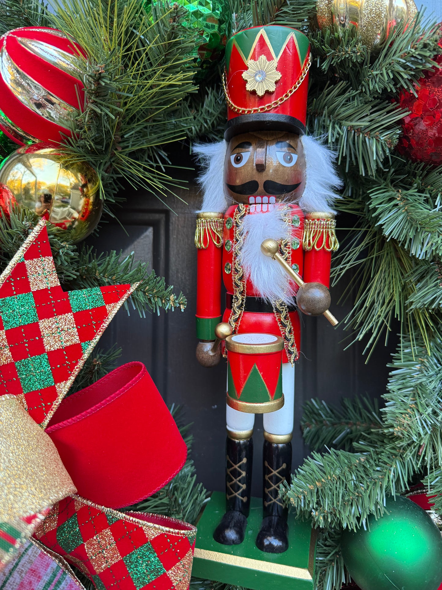 Decorative nutcracker figure on a Christmas wreath with ornaments.
